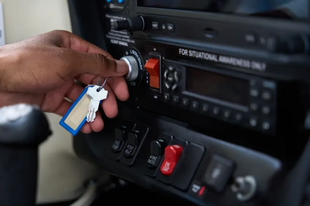 Student pilot performing aircraft preflight check by turning ignition switch in light aircraft cockpit during Private Pilot Licence training in Canada.